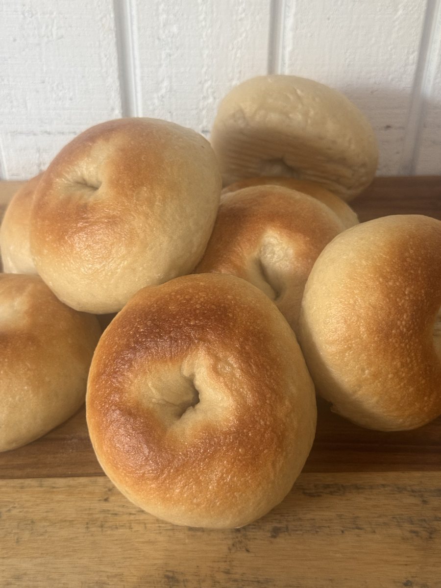 A stack of golden sourdough bagels on a wooden board