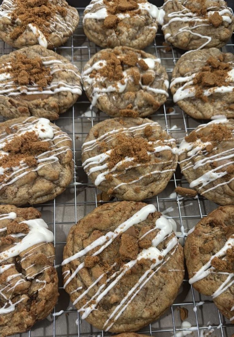 Biscoff cookies with white drizzle and cookie crumbs on a cooling rack