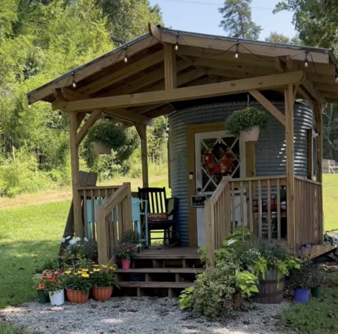 The silo farmstand porch with hanging mums, potted flowers and string lights