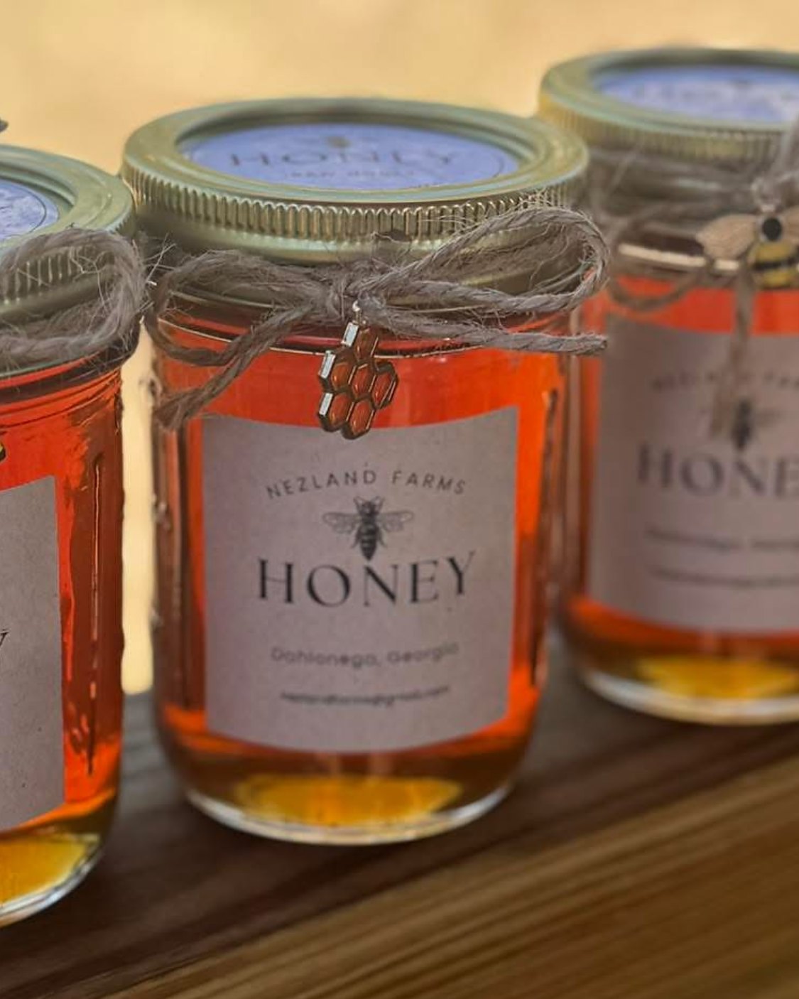Jars of Nezland Farms honey tied with twine and a honeycomb charm